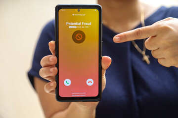 woman receiving call from fake on smartphone. The smartphone system detects potential fraud and...