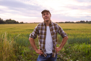 Farmer in front of a sunset agricultural landscape. Man in a countryside field. Country life, food production, farming and country lifestyle concept.