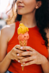 Closeup of a woman holding a double layered melting ice cream, on a hot summer day.