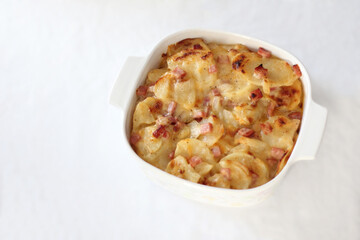 Gluten Free Cheesy Scalloped Potatoes and Ham Dish in White Ceramic Baking Dish with a White Background