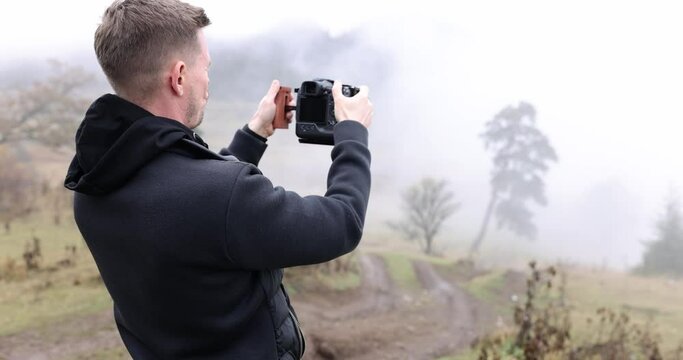 Photographer taking pictures of mountain landscape on camera 4k movie slow motion 