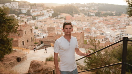 A tourist stands in front of an old town in Spain