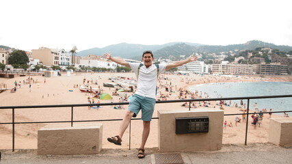 A tourist with a backpack is insanely happy to be on the beach. Vacation start