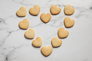 Freshly baked heart shaped shortbread cookies on marble background placed in a shape of a big heart
