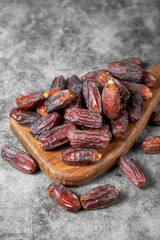 Date fruit on a dark background. Organic pile of medjoul dates on a wood serving board. Ramadan food. close up