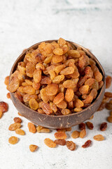 Raisins on stone background. Organic yellow raisins in a coconut bowl. Dried healthy nuts. close up