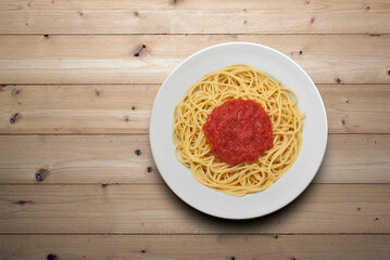 plate of spaghetti with tomato sauce, viewed from above on a wooden surface
