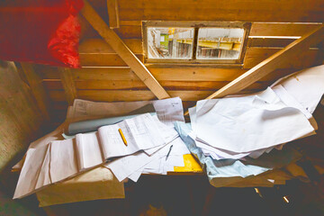 Bunch of architectural blueprints, plans, drawings in wooden office with small window with view on construction site