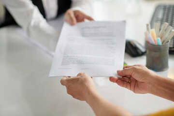 Hands of social worker giving documents to elderly woman