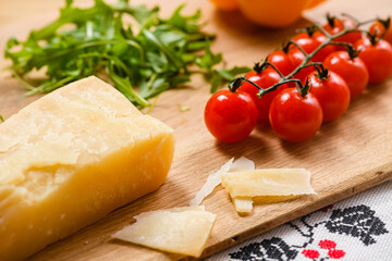 A piece of aged parmesan cheese on a wooden cutting board