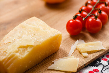 A piece of aged parmesan cheese on a wooden cutting board