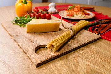 A bunch of whole grain spaghetti pasta tied with a string on a cutting board