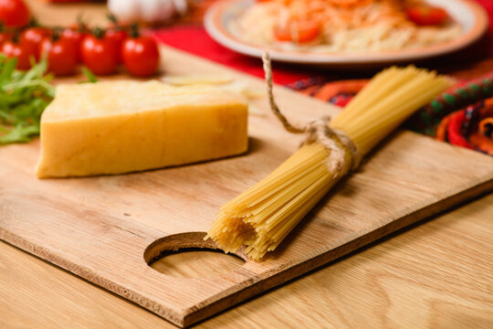 A bunch of whole grain spaghetti pasta tied with a string on a cutting board