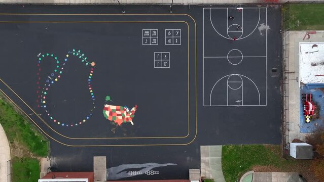 Top down aerial of asphalt playground at American school. Colorful paintings to play on at recess. United states fall, autumn playground theme.