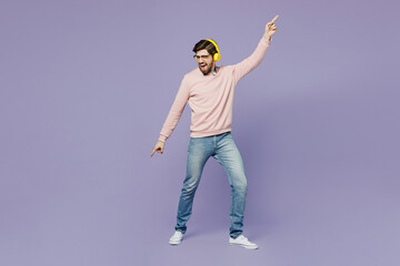 Fototapeta na wymiar Full body young excited IT man he wear casual clothes pink sweater glasses headphones dance listen to music dance gesticulating hands isolated on plain pastel light purple background studio portrait.