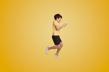 Fototapeta na wymiar Full body little small boy wearing yellow t-shirt holding mobile cell phone isolated on yellow background studio.