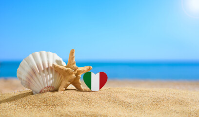 Beautiful beach in Italy. Flag of Italy in the shape of a heart and shells on a sandy beach. - obrazy, fototapety, plakaty