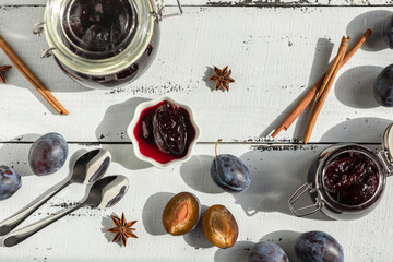 plum and prune fruit jam with spices on a white wooden background, the concept of canning at home, flat lay