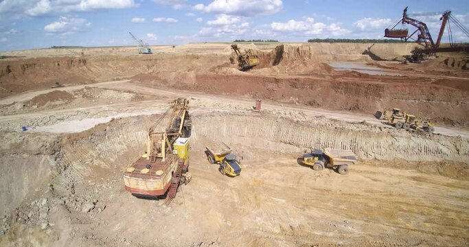 backhoe loader puts sand into quarry dump truck against working bucket wheel excavator and technics aerial view