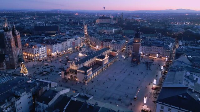 Przelot nad Rynkiem Gł&oacute;wnym w Krakowie po zachodzie słońca. Ratusz, Sukiennice, Kości&oacute;ł Mariacki, Wawel. Polskie zabytki widziane z drona.
