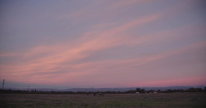 A pastel sky over the Sierra Nevada mountains with power lines and a shed in the foreground in Clovis, CA, USA