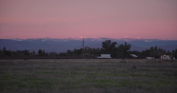 A pastel sky over the Sierra Nevada mountains with power lines and a shed in the foreground in Clovis, CA, USA