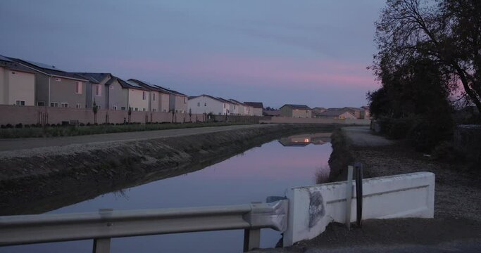A pastel sky over a canal with houses in the background in Clovis, CA, USA