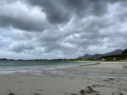 Wild empty beach, sandy coastline, dark cloudy sky, ocean bay