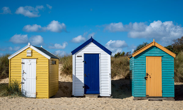 Three colourful beach huts on the Suffolk coast on a summer's day