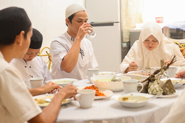 Muslim man in white koko shirt drink mineral water on glass, iftar ramadan and eid concept. 