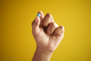 Fototapeta na wymiar man hand holding a medical pills against yellow background 