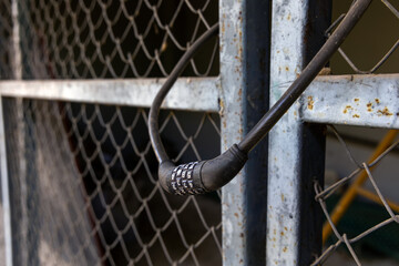 Combination lock with number wheels password code locked in chain link fence door.