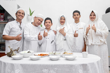 Smiling and happy muslim family showing thumbs up for delicious Eid food dishes at dining room
