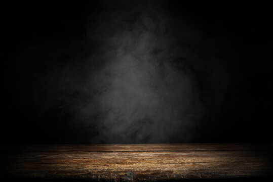 Dark empty wooden table with smoke float up on dark wall background. Free space for your decoration. © magdal3na