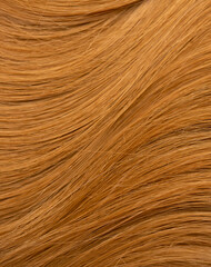 Red hair close-up as a background. Women's long orange hair. Beautifully styled wavy shiny curls. Hair coloring bright shades. Hairdressing procedures, extension.