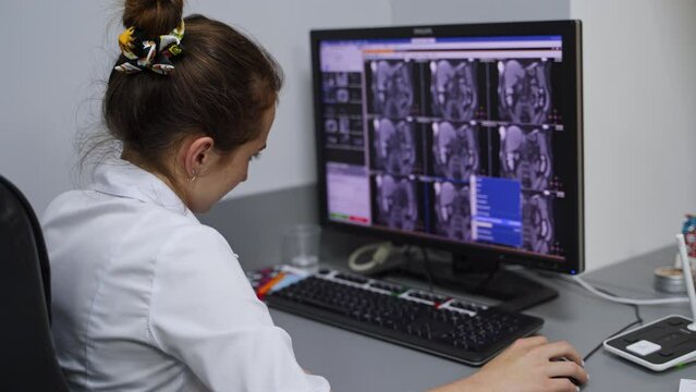 Young female lab specialist examining the scans from MRI diagnostics. Modern hospital lab for precise diagnose.