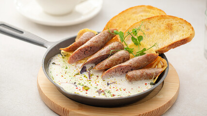 Portion of pan breakfast with sausages and cream sauce