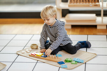 Child at kindergarten is playing with educational colorful montessori toy.