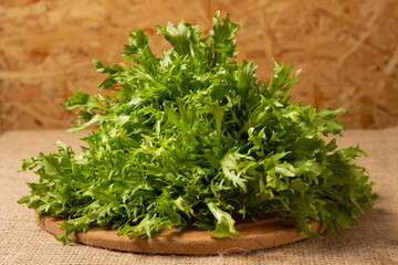 Large bunch of frisee lettuce on a round wooden board