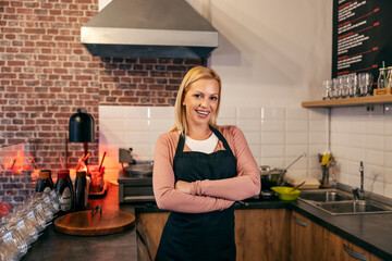 A small business owner is standing at pancake shop with arms crossed and smiling at the camera.