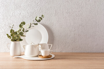 items for the tea ceremony on the kitchen wooden countertop. a branch of eucalyptus in a white vase. minimalist kitchen background with a copy space.