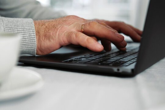 Closeup Of Senior Man Hands Using Laptop. Cropped Side View Of Wrinkled Caucasian Older Hands Typing Keyboard. Old People With Technology. Unrecognizable Retired Male Working From Home Sitting At Desk