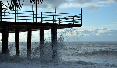The wave crashes against the pier