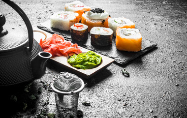 Pieces of delicious Japanese sushi rolls with green tea and sauces.