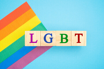 Wooden cubes with the letters LGBT on a rainbow flag or LGBT flag on a blue background