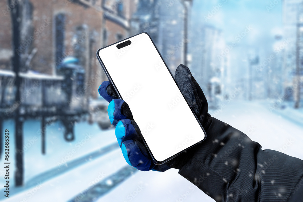 Poster Using a mobile phone on the street while it is snowing. Isolated display for app promotion. Man's hand holding a phone with a winter glove