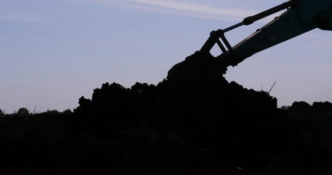 silhouette of a backhoe working,excavator at sandpit during earthmoving works,Excavator in construction site 