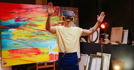 Portrait of young Caucasian creative talented man artist stands in art studio wearing virtual reality glasses moving hands in air creating new project, innovative technology, VR headset, art concept