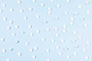 White tablets pattern in hard light on soft light blue color, top view. Medical and pharmacy remedies for health and prevent, teraphy disease background in simple modern style - home medicine chest.