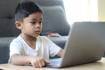 Asian schoolboy doing her homework with laptop at home. Children use gadgets to study. Education and distance learning for kids. Homeschooling during quarantine. Stay at home